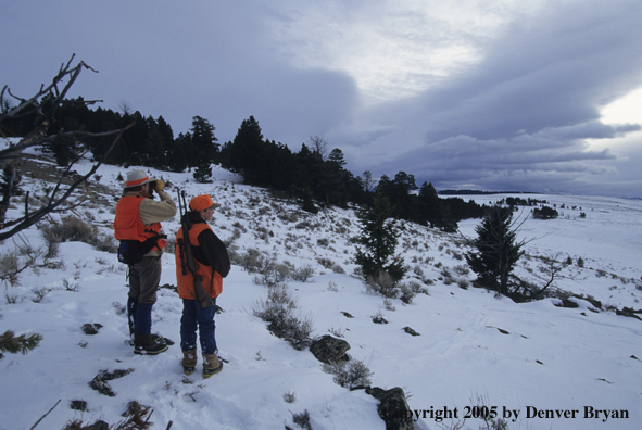 Father and son hunters big game hunting in a field in winter.