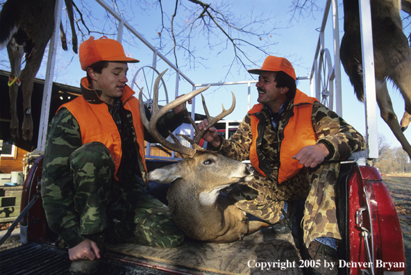 Father and son hunters with whitetail deer in truck.