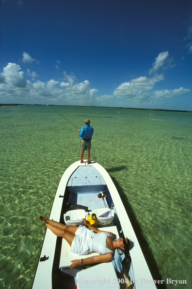 Saltwater flyfisherman casting from boat, woman sunbathing.