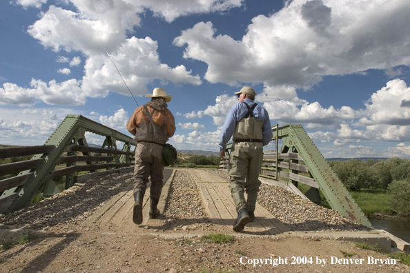 Flyfishermen walking across bridge.