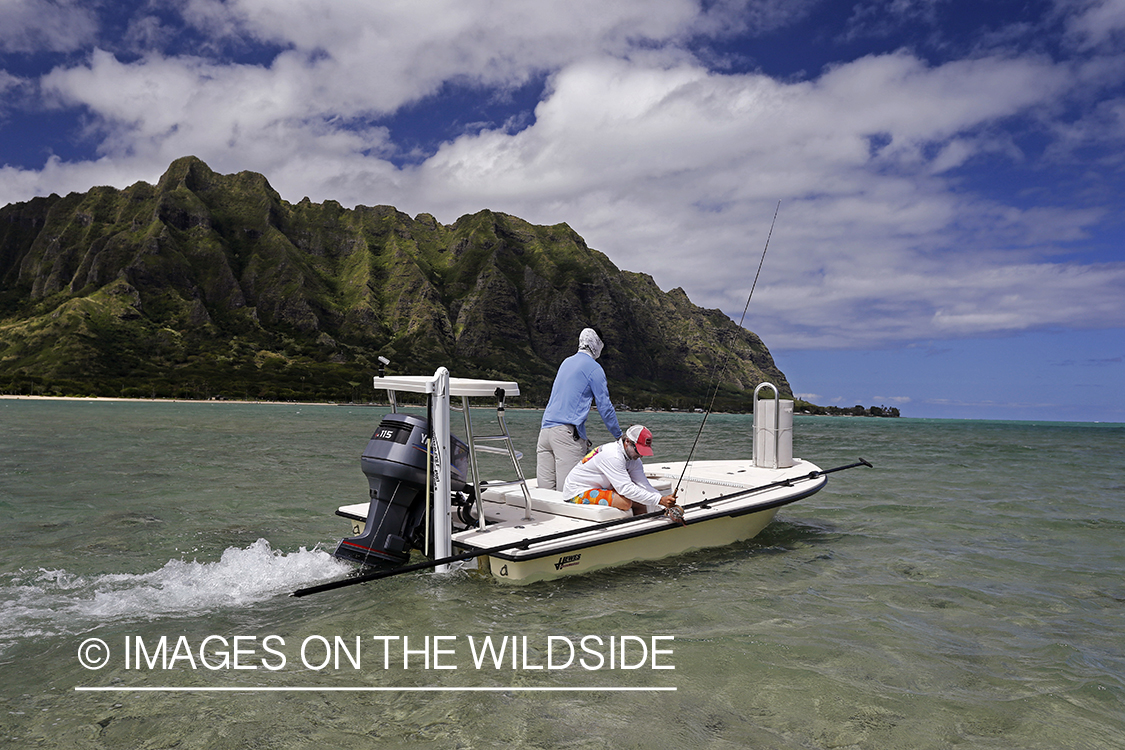 Saltwater flyfishermen fishing on flats boat, in Hawaii.