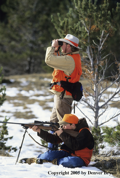 Father and son hunters big game hunting in a field in winter.