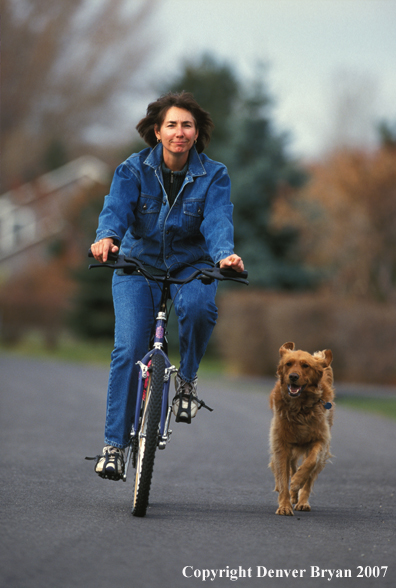 Biker riding with dog running below