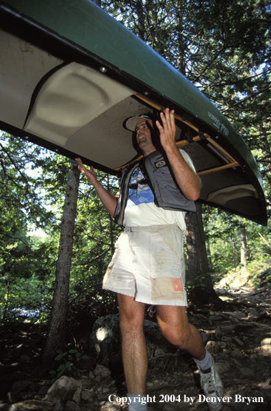 Flyfisherman portaging canoe.