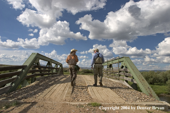 Flyfishermen walking across bridge.