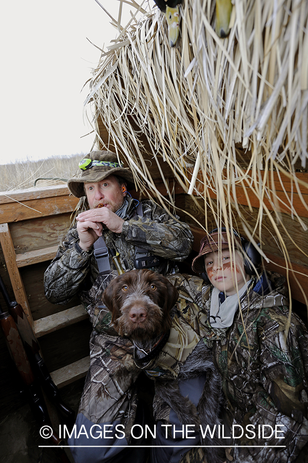 Father and son waterfowl hunters calling waterfowl.