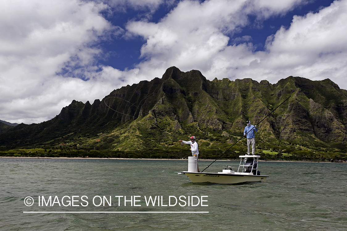 Saltwater flyfishermen fishing on flats boat, in Hawaii.