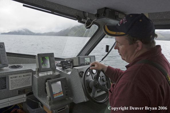 Fishing boat captain at the helm driving the boat.  (Alaska/Canada)