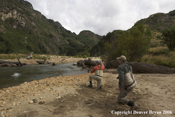 Flyfisherman fighting fish from bank.