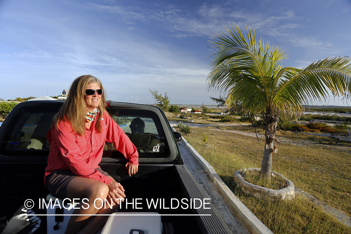 Woman riding in bed of truck to go saltwater flyfishing.