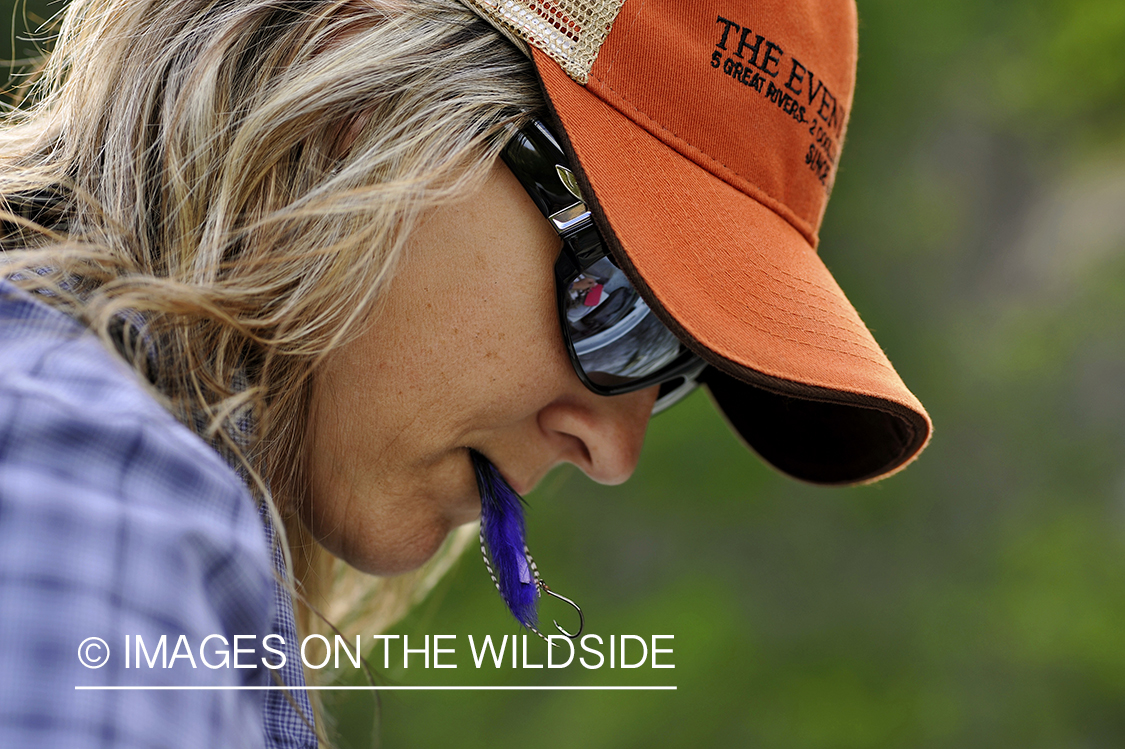 Woman flyfisher tying on fly. 