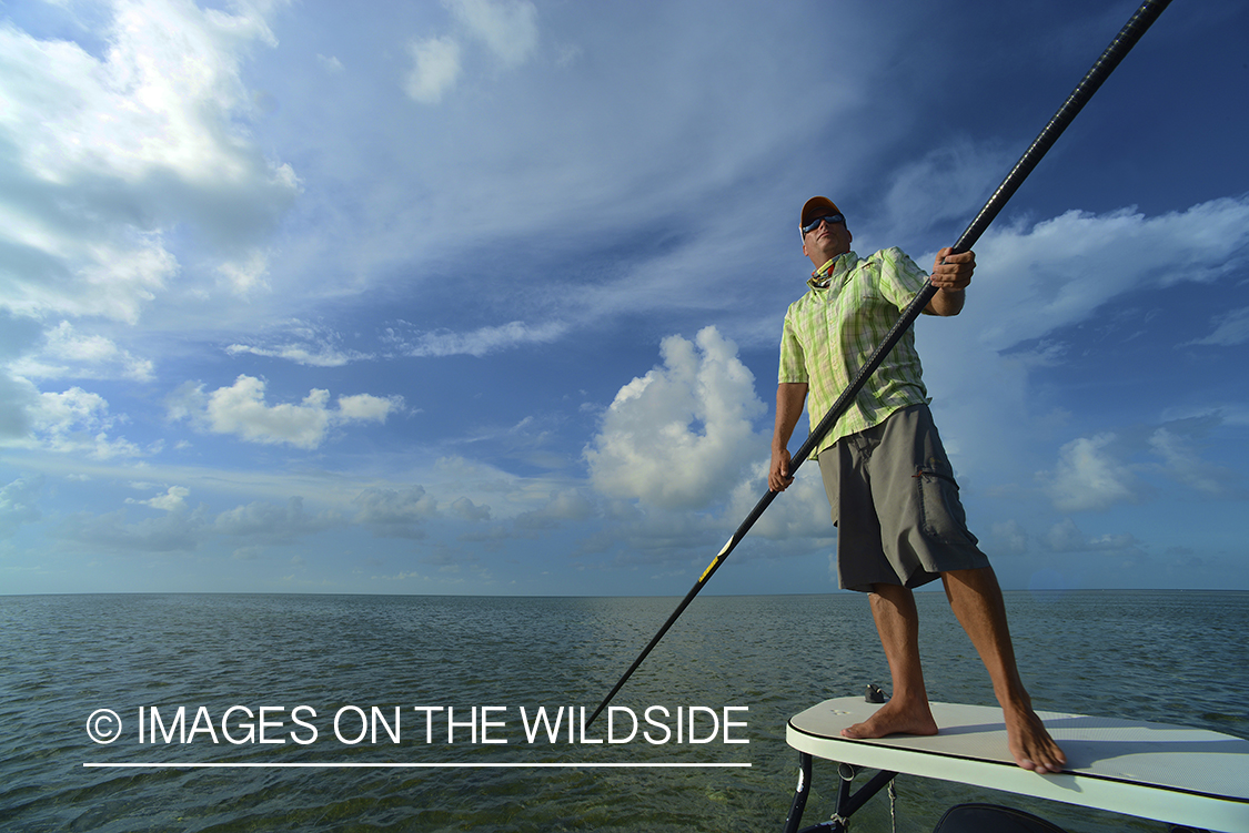 Saltwater flyfisherman poling flats boat.