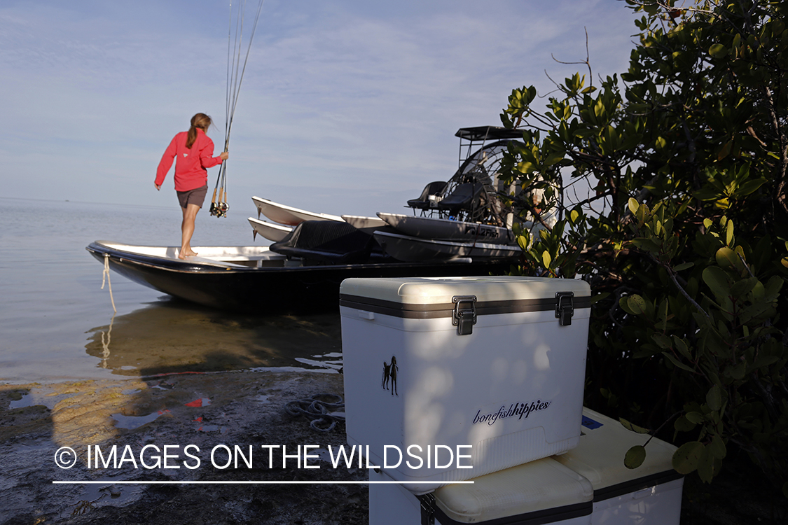 Saltwater flyfishing woman loading rods on airboat.