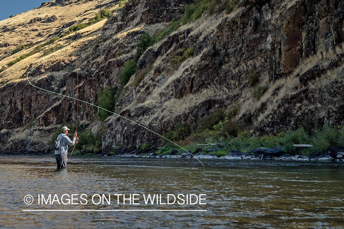 Flyfisherman casting spey rod on stream.