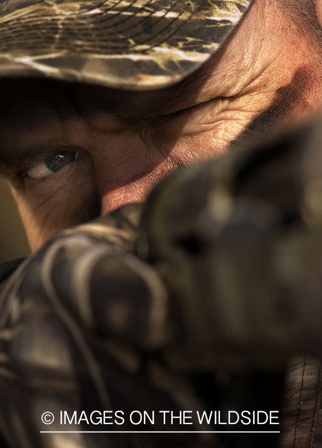 Waterfowl hunter taking aim in wetlands.