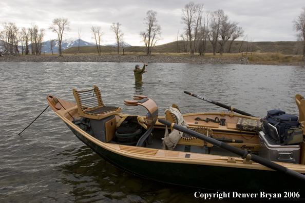 Drift boat on river with flyfisherman in background.