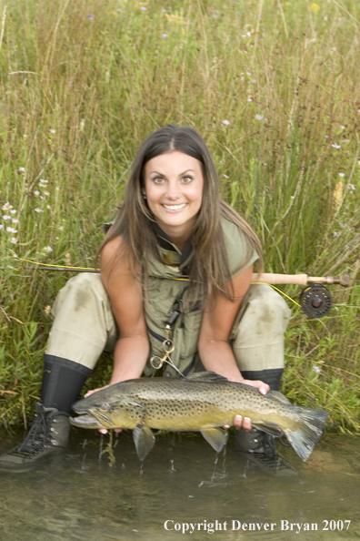 Woman flyfisher with large brown trout.