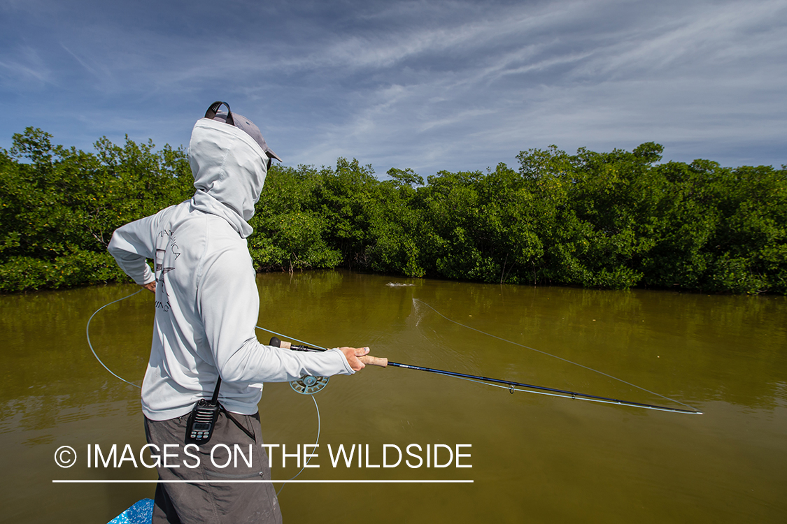 Flyfishing woman fighting fish from boat.