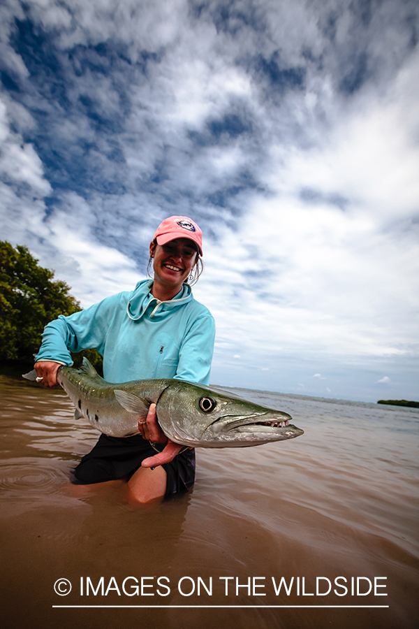 Flyfishing woman releasing barracuda.