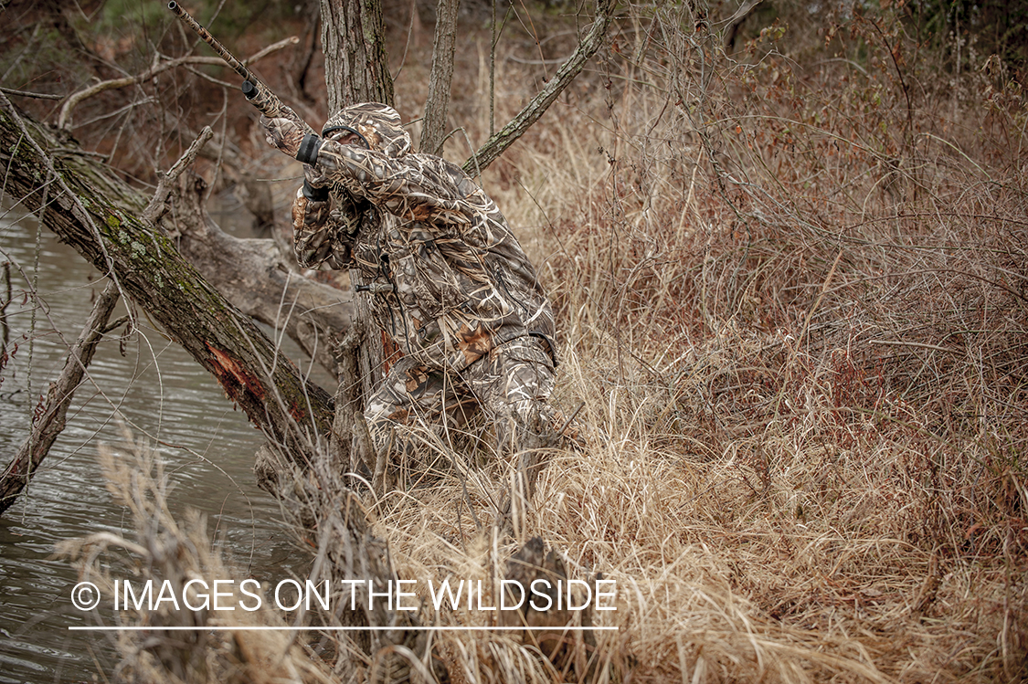 Waterfowl hunter taking aim in wetlands.