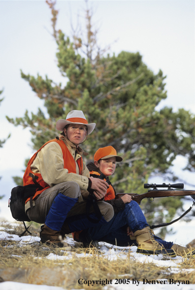 Father and son hunters big game hunting in a field in winter.