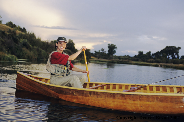 Woman flyfisher in cedar canoe.