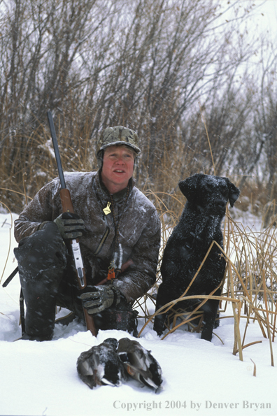 Waterfowl hunter with black Lab and ducks. 