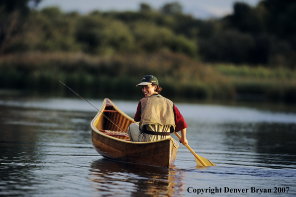 Woman flyfisher in cedar canoe.