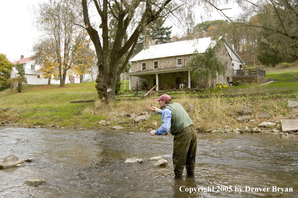 Flyfisherman on Pennsylvania spring creek with club house in background.