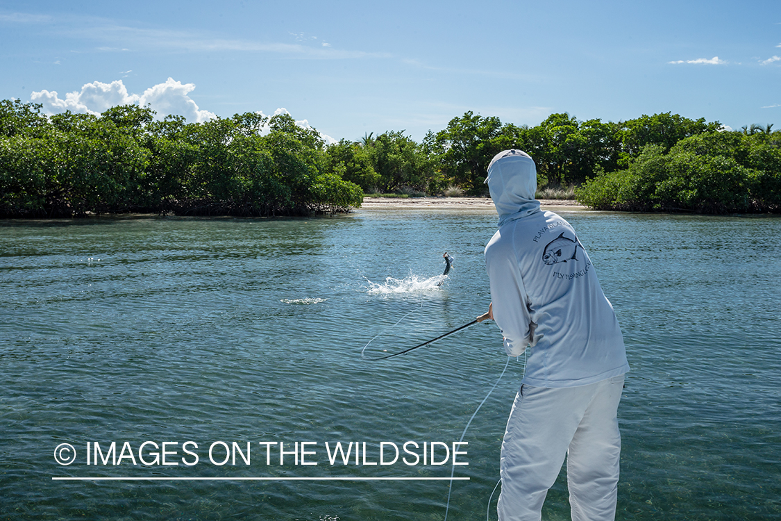 Flyfishing woman fighting fish from boat.