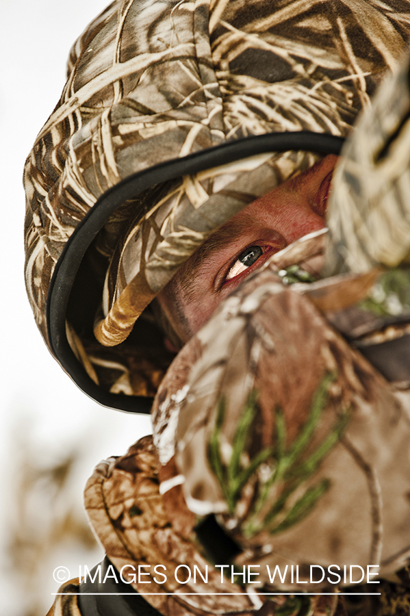 Waterfowl hunter taking aim in wetlands.