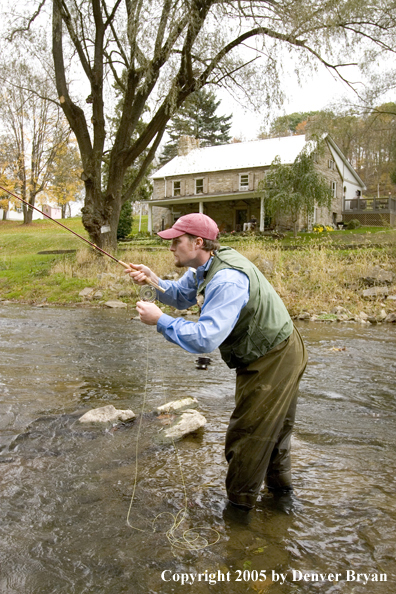 Flyfisherman on Pennsylvania spring creek with club house in background.