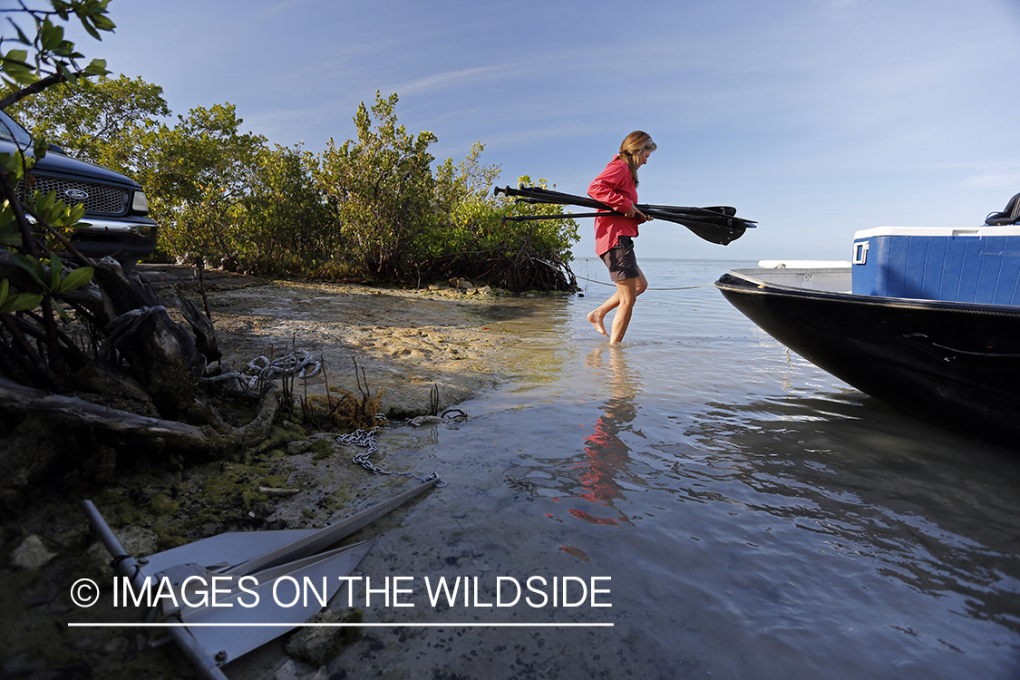 Saltwater flyfishing woman loading paddles on airboat.