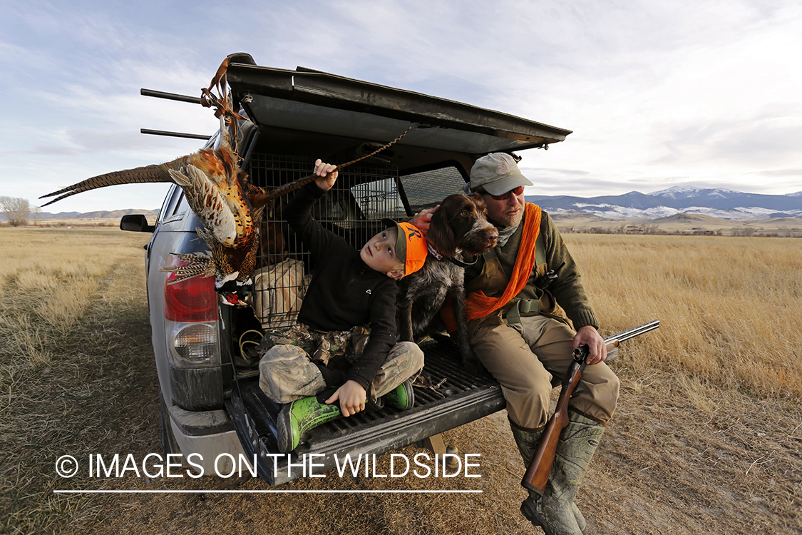 Father and son pheasant hunters with bagged pheasant. 