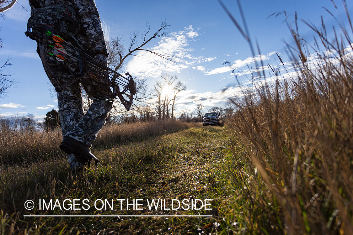 Bow hunter walking in field.