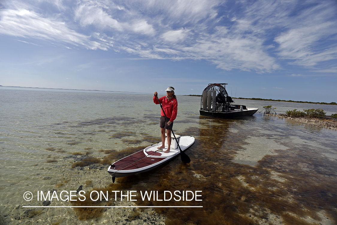 Saltwater flyfishing woman leaving airboat on paddle board.