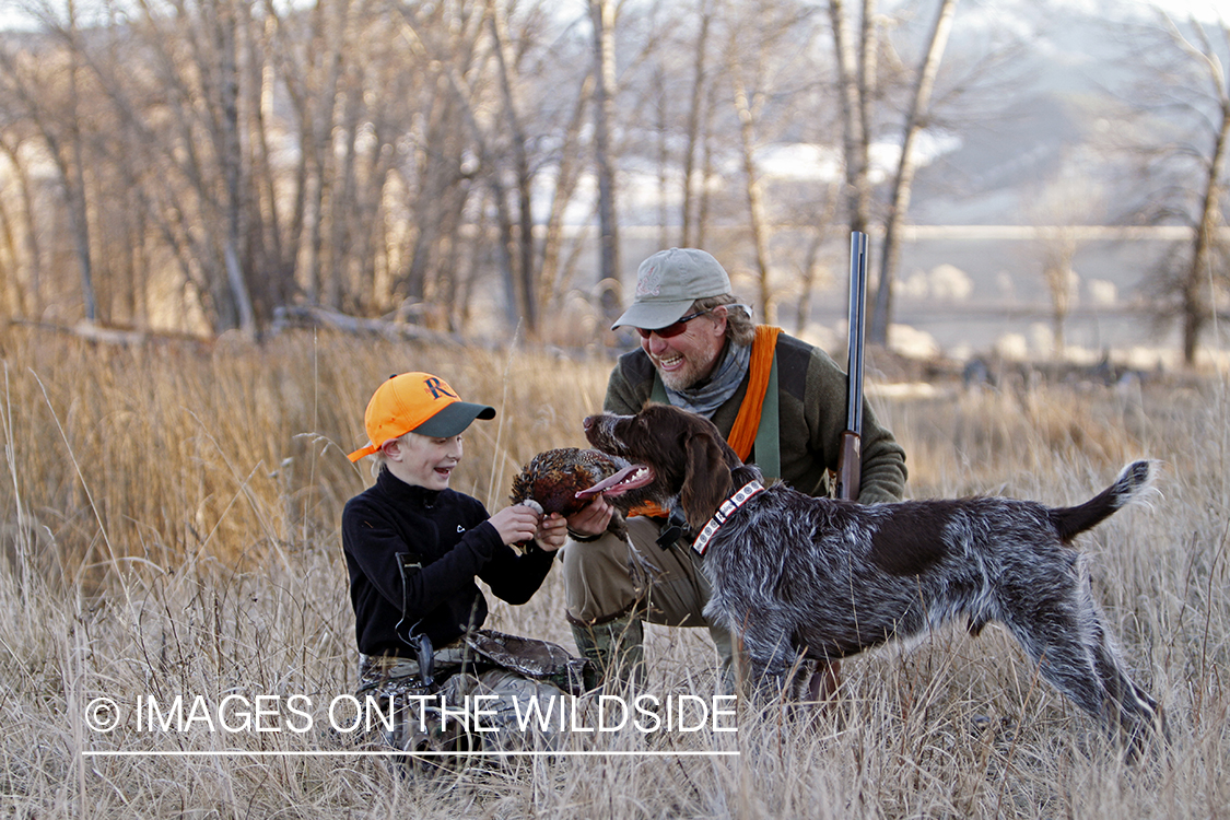 Father and son pheasant hunters with bagged pheasant. 