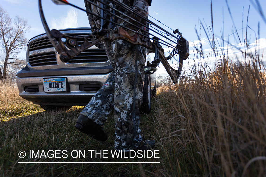 Bow hunter walking in field.