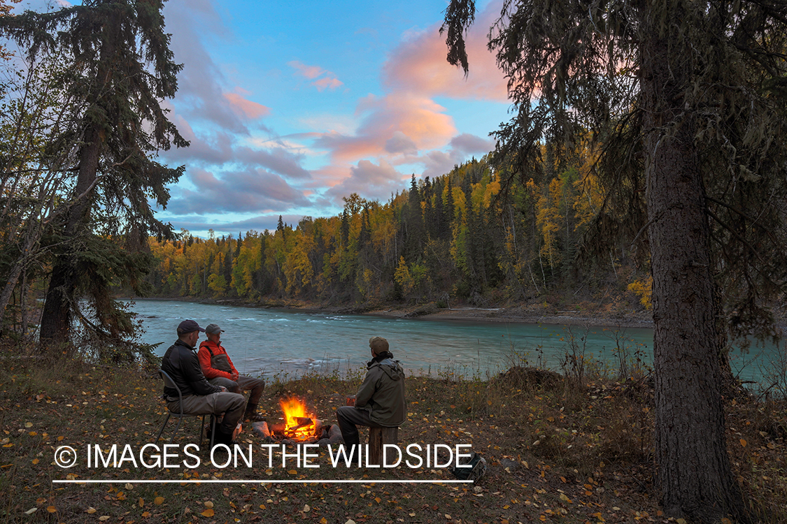 Flyfishermen at camp on edge of river.