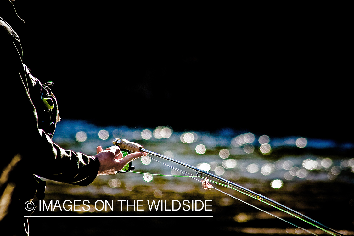 Flyfisherman balancing fly rod on finger.