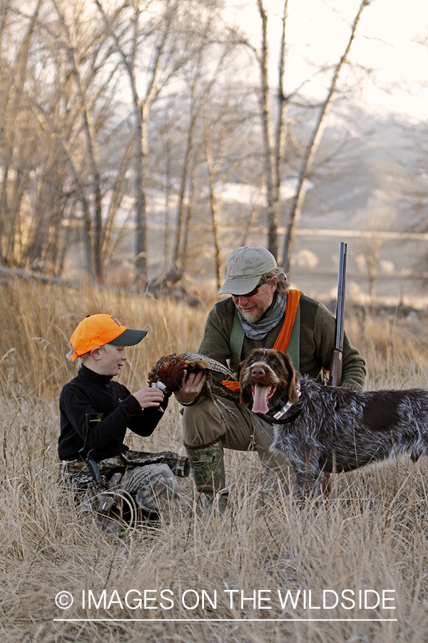 Father and son pheasant hunters with bagged pheasant. 