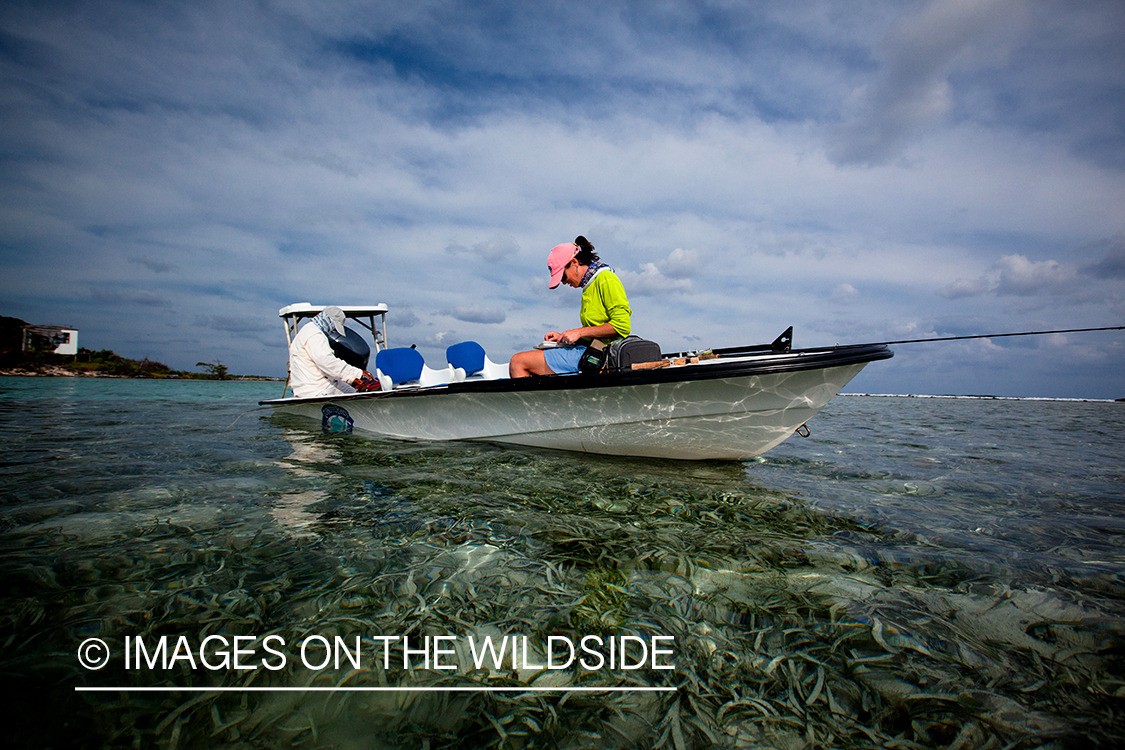 Woman flyfisherman checking flies on saltwater flats boat.