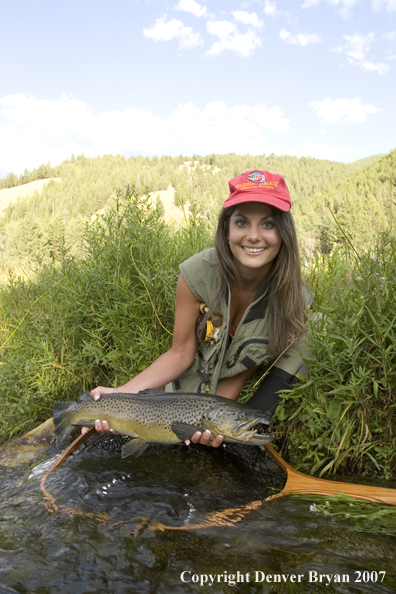 Woman flyfisher with large brown trout.