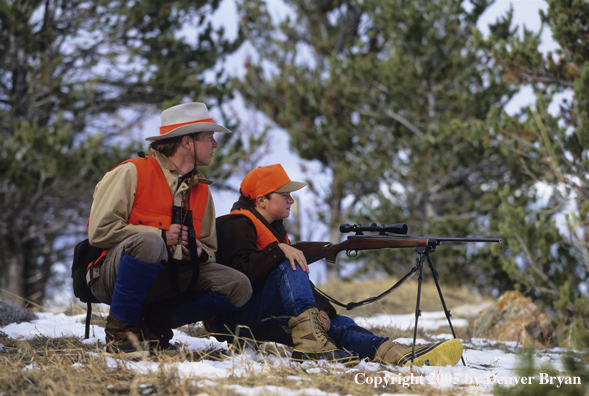 Father and son hunters big game hunting in a field in winter.