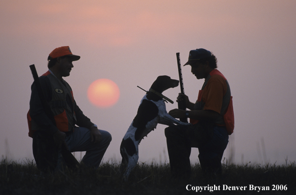 Upland game bird hunters with dog at sunset.