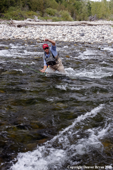 Flyfisherman slipping on river rocks