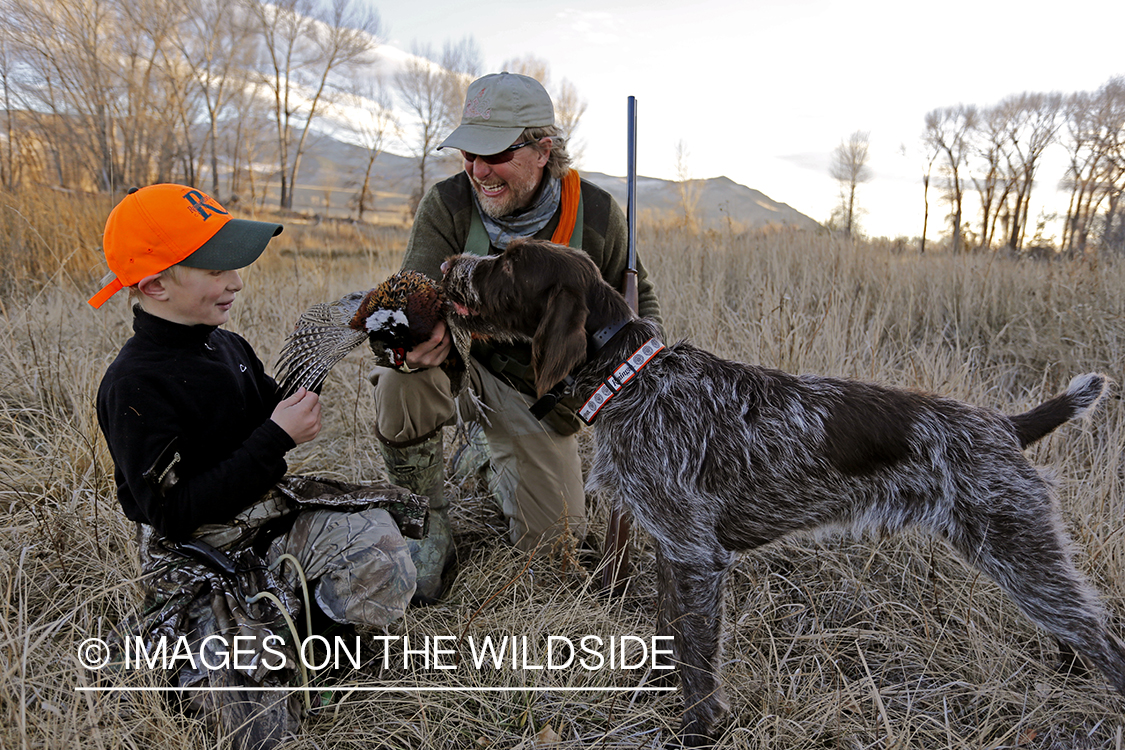 Father and son pheasant hunters with bagged pheasant. 