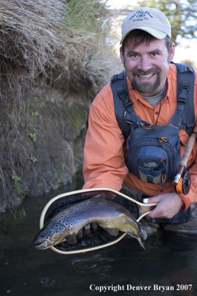 Flyfisherman holding brown trout.