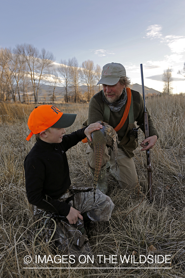 Father and son pheasant hunters with bagged pheasant. 