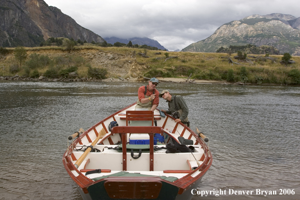 Flyfishermen checking out fly at driftboat.